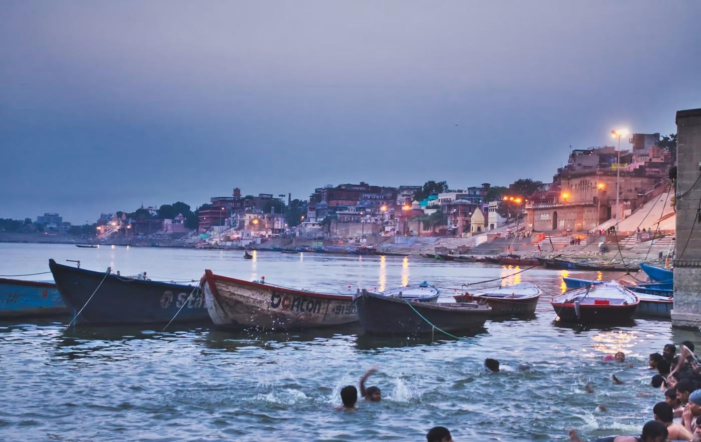 Wooden boats moored at the ghats at dusk, pilgrims at the water's edge